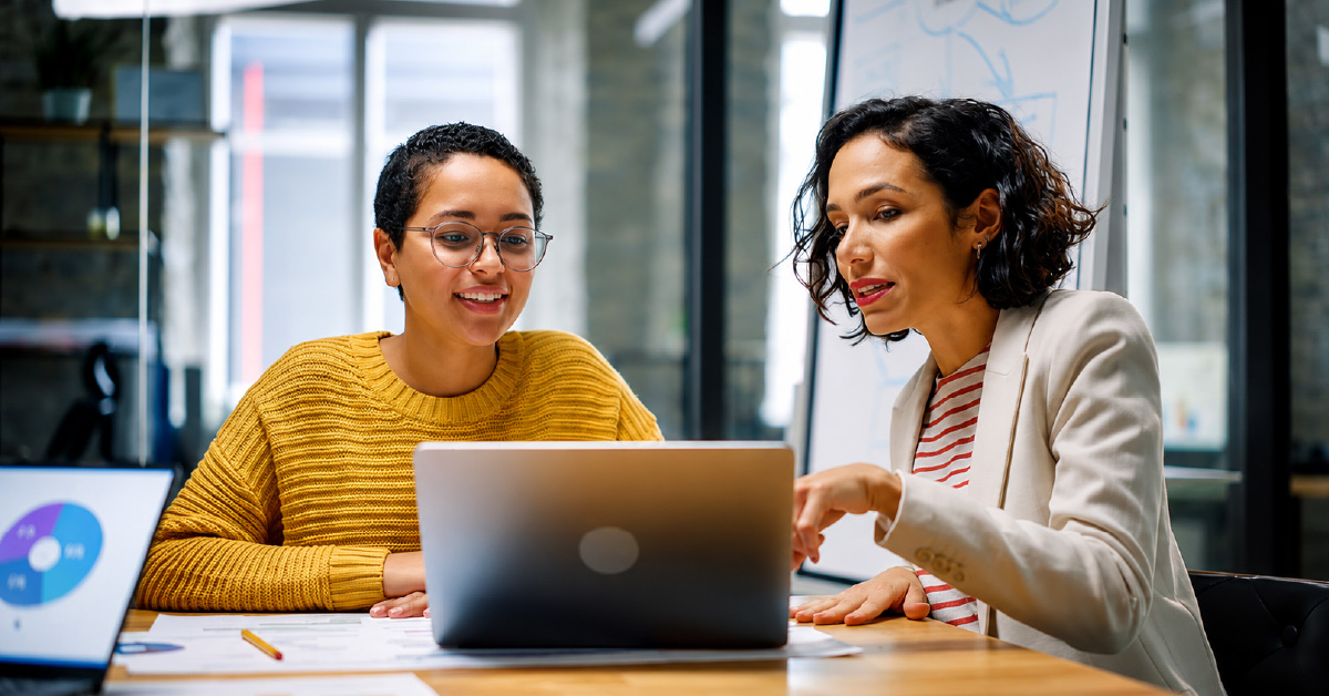Two colleagues reviewing performance data together on a laptop